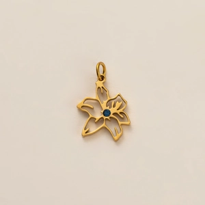 Détail d'un pendentif fleur dorée avec zircon bleu et design ajouré élégant