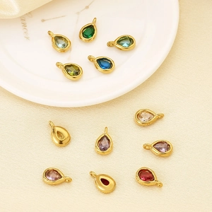 Eleven multi-colored teardrop pendants in gold-plated stainless steel on a white dish