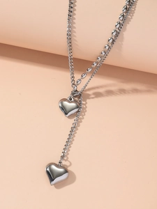 Detail of silver double-layered necklace with heart pendants and polished chain textures