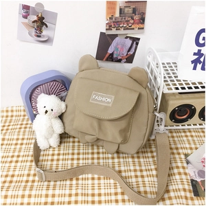 Detail of khaki nylon crossbody bag with 3D animal ears and white plush bear charm