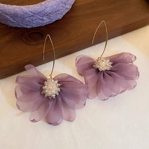 Detailed view of purple mesh tassel earrings with white flower beads and gold long hooks