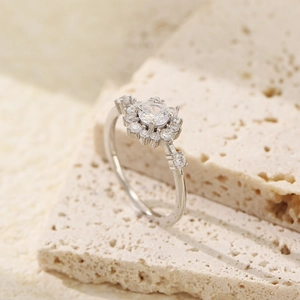 Macro detail of silver floral ring with a central sparkling zircon on a stone surface
