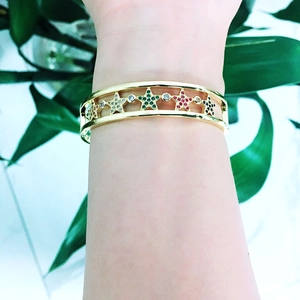Detail of gold hollow star bracelet with colorful zircon stones on model's wrist