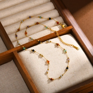 Golden stainless steel necklace with multi-colored natural stone beads on a jewelry box