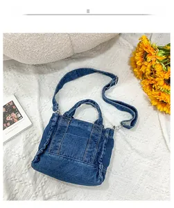 Detail of vintage blue denim tote bag featuring orange contrast stitching and adjustable strap