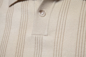 Nahaufnahme von beigem Strick-Polo mit Streifenmuster und einem eleganten runden Knopf