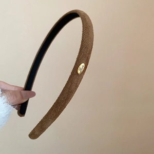Détail d'un serre-tête en velours marron orné d'une boucle métallique dorée Love élégante