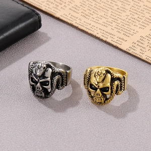 Detail of hip hop snake and skull ring in gold and silver finish on a dark background