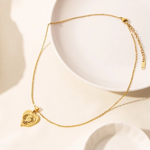 Detail of 18k gold plated stainless steel heart pendant with sunburst texture on white plate