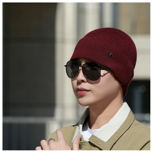 Close-up of burgundy ribbed knit beanie with small black metal logo tag detail