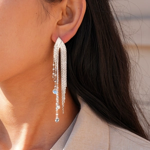Gros plan de longues boucles d'oreilles à pompons argentés avec détails de chaîne
