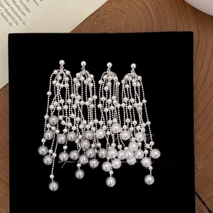 Detail of silver tassel earrings with white and grey pearls on vintage book background
