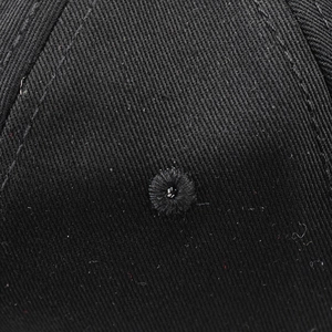 Gros plan sur le sergé de coton noir montrant la broderie 3D et l'œillet d'aération