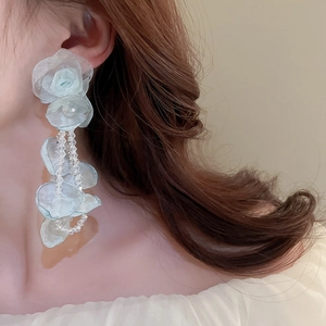 Detail of light blue tulle flower earrings with crystal tassels on a female model