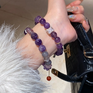 Close-up of model wearing purple amethyst beaded bracelets with a luxury croc leather bag