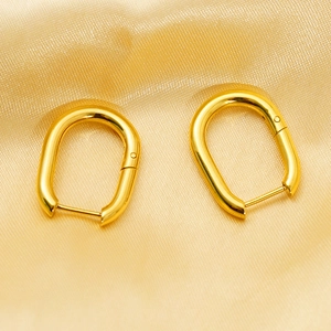 Detailed view of U-shaped gold titanium earrings on a luxurious silk fabric background