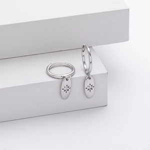 Detailed view of S925 silver hoop earrings with starburst zircon compass charms on white steps