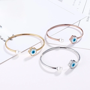 Detailed view of open bangles in gold, silver, and rose gold with evil eye and pearls