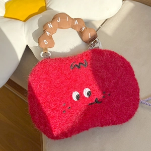 Macro detail of red plush handbag featuring cartoon embroidery and brown cotton handles