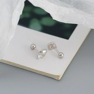Close-up of S925 sterling silver heart stud earrings with cubic zirconia on an open book