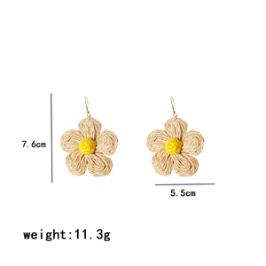 Detail showing dimensions of yellow hand-woven raffia flower earrings on white backdrop