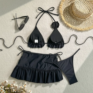 Detailed flat lay of a black three-piece bikini set with decorative 3D flower and sunhat