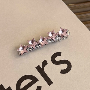 Detailed close-up of a silver hair clip with five pink star-shaped crystals