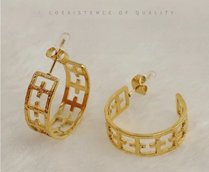 Détail des boucles d'oreilles en forme de C en acier plaqué or 18K avec motifs croix