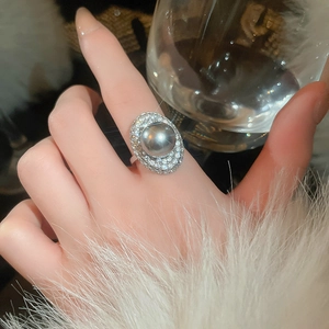 Detail of French vintage pearl ring with zircon halo on model hand with elegant lighting