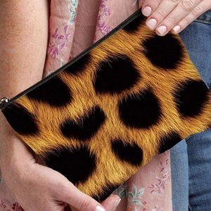 Stylish leopard print canvas makeup bag held by hand, featuring a secure black zipper