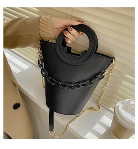Detail of black PU bucket bag with unique round handle and acrylic chain strap