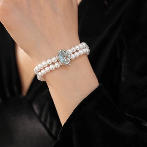 Détail d'un bracelet en perles à double rang avec un grand fermoir en pierre bleue ovale