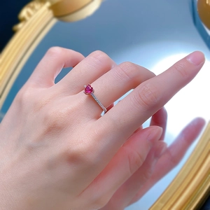 Close-up of heart-shaped red gemstone ring with side-set diamonds on silver band