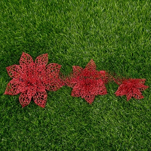 Three-piece set of red glitter hollow poinsettia flowers on green grass background