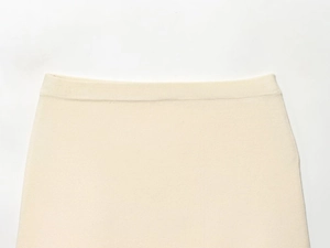 Close-up of the elastic waistband on a cream knit mini skirt with ribbed texture