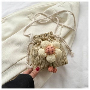 Dettaglio mini borsa a secchiello in paglia con grande fiore di stoffa e pompon arancioni