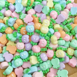 Macro shot of colorful mini resin apple charms with cute expressions for DIY nail art crafts