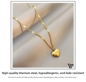 Macro detail of gold-plated heart pendant with Love engraving on a fine titanium chain