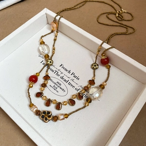 Vue macro du collier de perles vintage avec breloques en résine et fleurs dorées