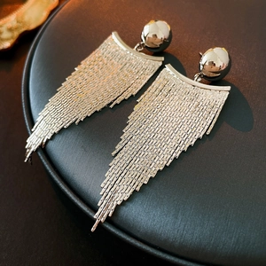 Close-up of silver tassel earrings with geometric chains on a black display stand