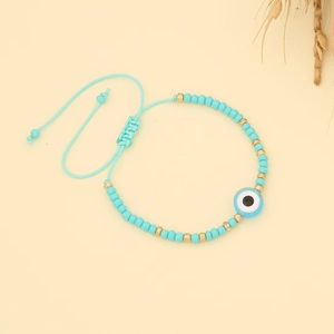 Macro detail of Bohemian evil eye bracelet with light blue beads and adjustable cord