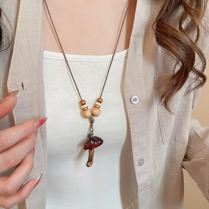 Detail of handmade resin mushroom pendant necklace with natural wood beads on wax cord