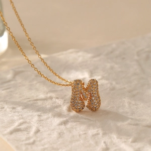 Macro shot of gold-plated letter M pendant set with sparkling cubic zirconia crystals