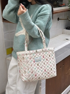 Close-up of quilted cotton tote bag featuring cute cartoon animal prints and a blue woven label
