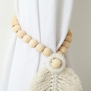 Close-up of bohemian curtain tieback with natural wooden beads and woven leaf tassel