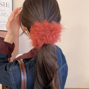 Close-up of a large coral pink plush scrunchie showing fluffy texture on a ponytail
