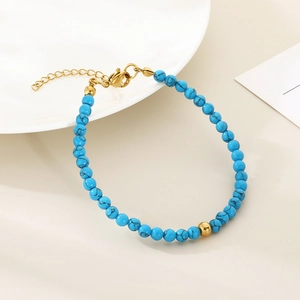 Detailed macro of blue turquoise bead bracelet with gold lobster clasp and chain