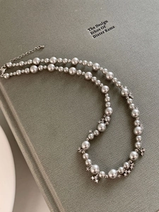 Detail of silver pearl necklace with cross pendants on a vintage textured book background
