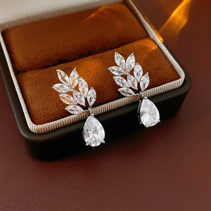 Macro detail of silver drop earrings with marquise zircon leaves on brown velvet