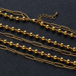 Detail of layered gold beaded and oval link chain necklace with a lobster clasp